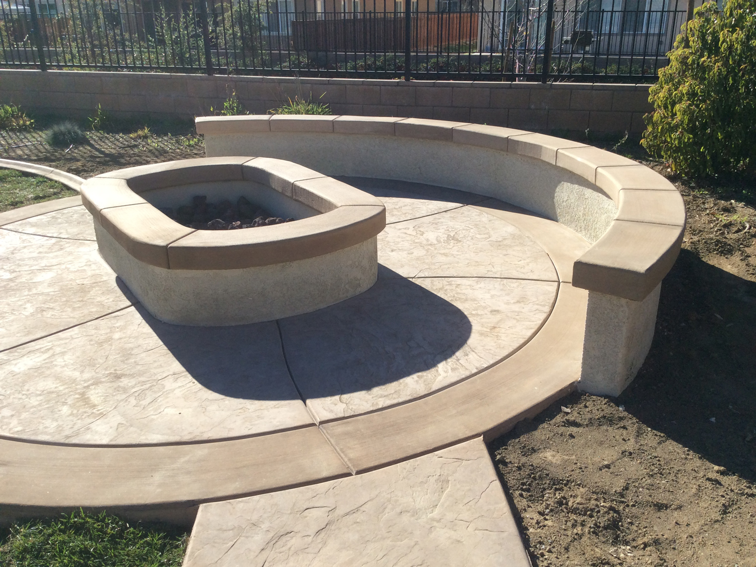 Fire pit with sitting wall and colored concrete in Menifee McCabe's Landscape Construction