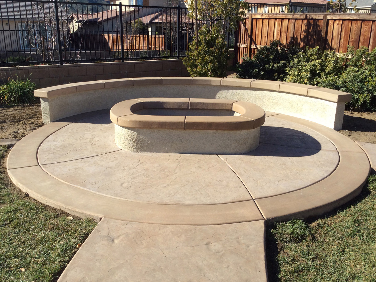 Oval fire pit with sitting wall and colored concrete in Mennifee McCabe's Landscape Construction