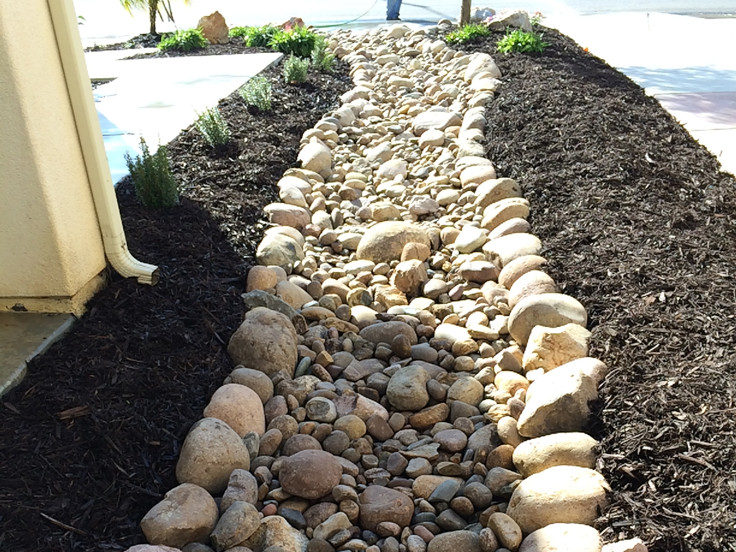 Dry river bed and mulch beds on the side of a house.