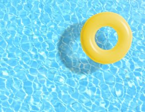 Yellow swimming pool ring float in blue water. concept color summer.