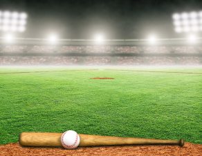 Baseball bat and ball on field at brightly lit outdoor stadium.