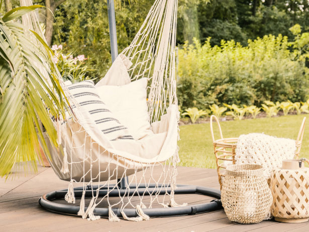 Lanterns and basket between rattan sofa and hammock with pillows in the garden.