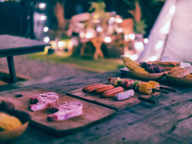 Family making barbecue in dinner party camping at night with bokeh light bulb and tent