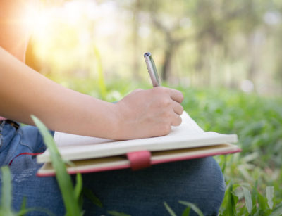 Person writing about nature in their journal outside.