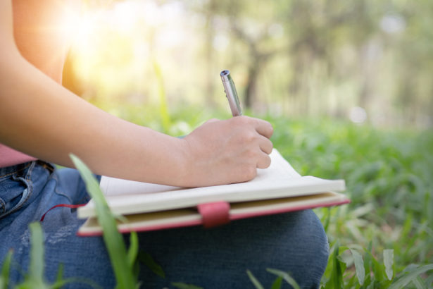 Person writing about nature in their journal outside.