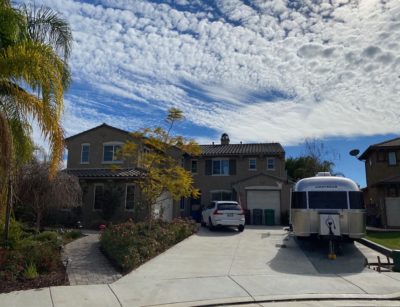 Airstream parked in front yard of a home using a driveway extension and curb.