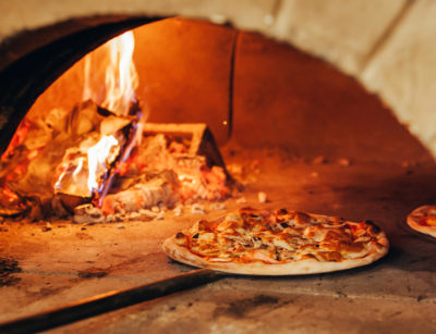 Pizza cooked in an outdoor brick oven.