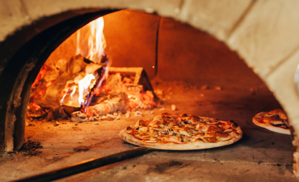 Pizza cooked in an outdoor brick oven.